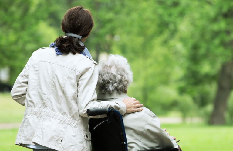 A caregiver and an elderly person enjoying a peaceful moment in a park.